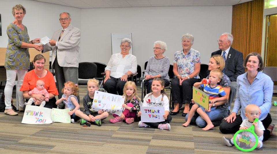Helen Whitehouse (first left) is presented with a cheque, on behalf of the Morecambe Masonic Fellowship, from Tom Hunter, together with other members of the fellowship (seated), whilst surrounded by children and parents from the charity.