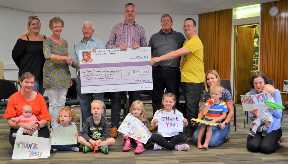 Helen Whitehouse (second left), receives a cheque from Jim Wilson, Ben Yates and group chairman Neil McGill (centre, left to right), whilst surrounded by children and parents from the charity.