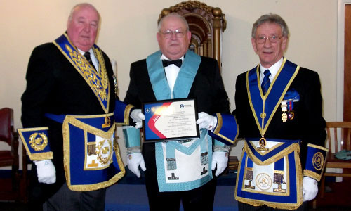 Peter Levick (left) presents John Reed with the lodge’s certificate of Grand Patronage for the 2021 Festival with Malcolm Sandywell (right) watching on. Peter Levick (left) presents John Reed with the lodge’s certificate of Grand Patronage for the 2021 Festival with Malcolm Sandywell (right) watching on.