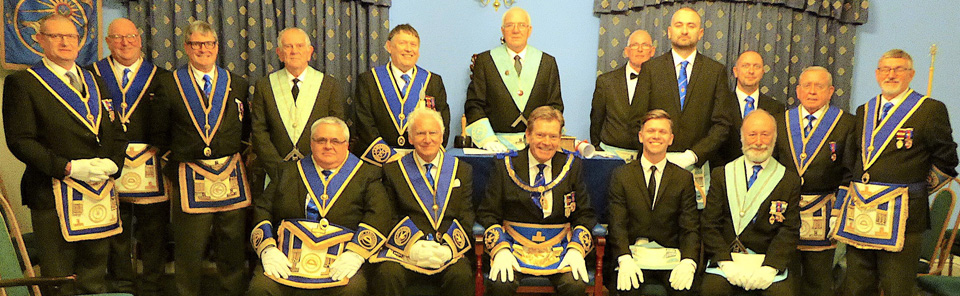 Assistant Provincial Grand Master Kevin Poynton (seated centre) surrounded by brethren of the lodge and visitors, with WM John bell standing back centre. Assistant Provincial Grand Master Kevin Poynton (seated centre) surrounded by brethren of the lodge and visitors, with WM John bell standing back centre.