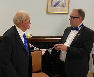 Arnold (left) is presented with a 50th celebration badge by the WM, Martin Stewart.