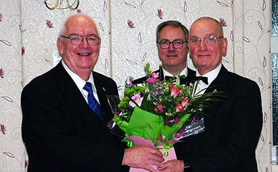 Ted Rhodes (left) is presented with flowers by Barry Thompson with Brian Coulter in the background.
