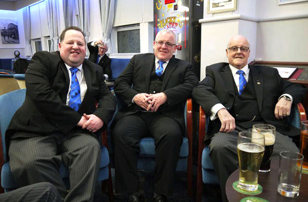 Pictured from left to right, are: Gary Harper, Jim Harper Jnr and Jim Harper (with Terry Barlow in the background giving a belated toast to the celebrant).