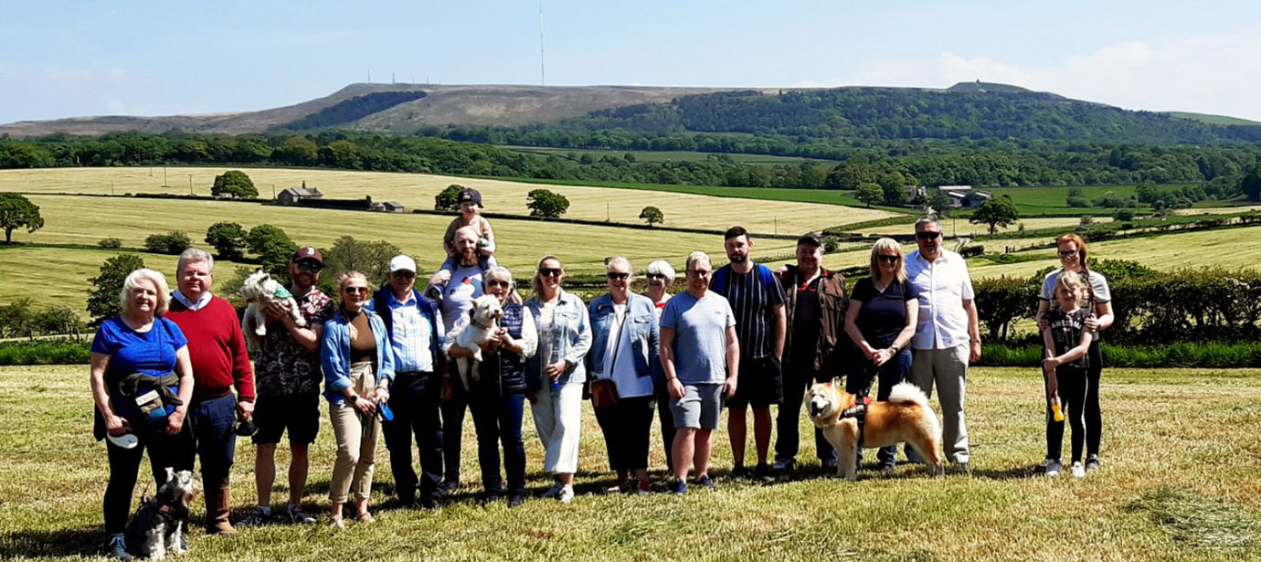 The walkers, including their canine family members, standing against the beautiful backdrop of Winter Hill and Rivington Pike.