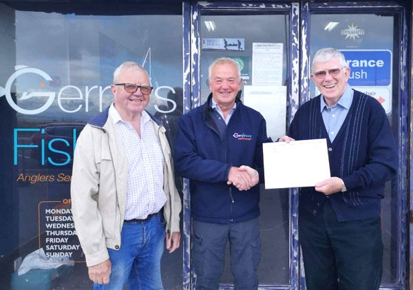 Pictured from left to right at Gerry`s Fishing Emporium, are: Keith and Gerry receiving his Certificate of Merit from Tony.