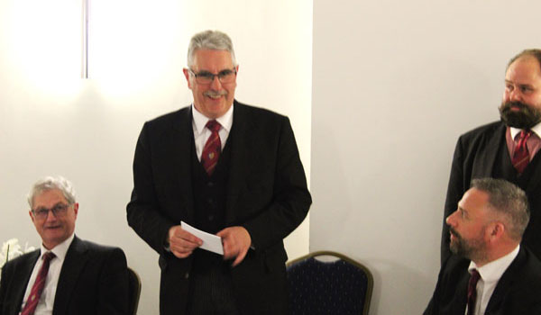 Andrew Barton responding to his toast with Gareth Jones (left), Chris Hanson (seated right) and Ezra McGowan (standing right), listening attentively.