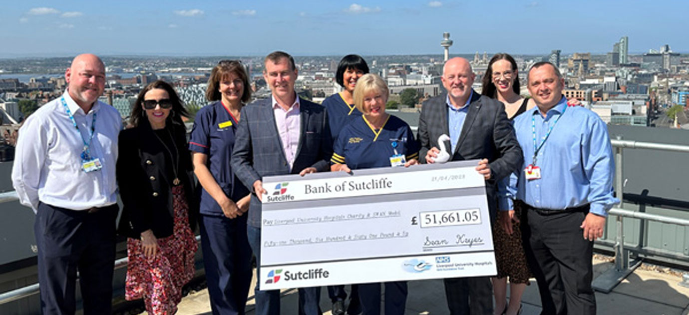 Presentation of the cheque to RLUH SWAN model, Sean (holding the cheque, left) and Fiona surrounded by staff from the hospital team and directors of Sutcliffe on the new hospital roof.