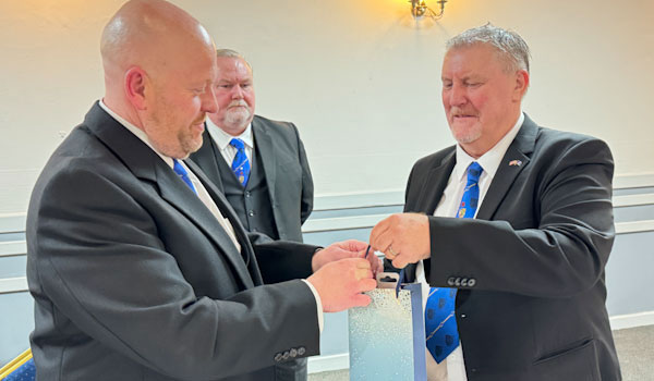 Malcolm (left) receives a thank you gift from Mick. Malcolm (left) receives a thank you gift from Mick.